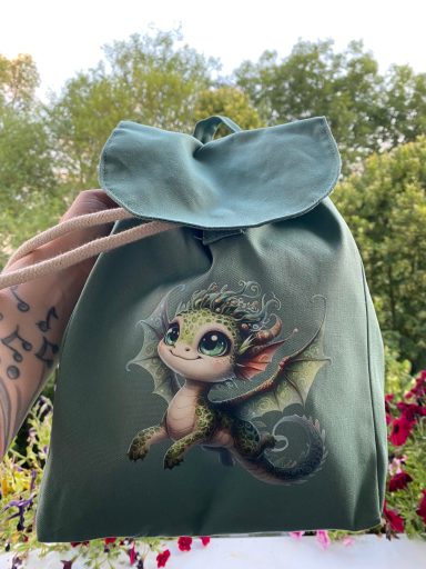 Grüne Tasche mit einem niedlichen Drachenmotiv auf der Vorderseite.