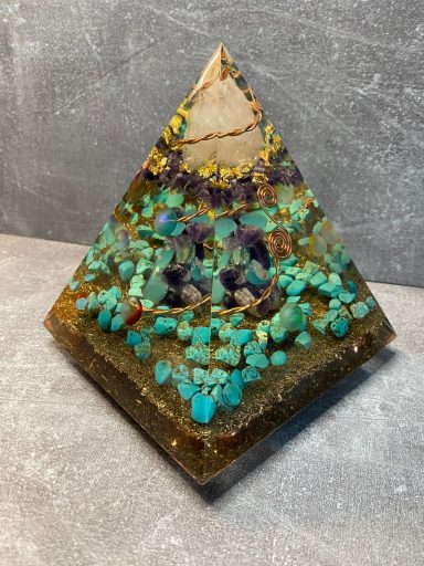 Pyramide aus Harz mit türkisfarbenen und lila Mineralien, auf grauem Hintergrund.