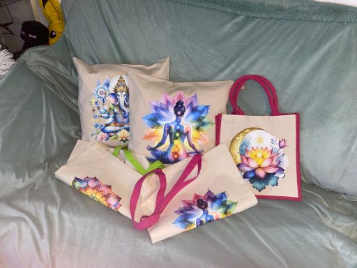 Bunte handgezeichnete Kissen und Taschen auf einem grauen Sofa.