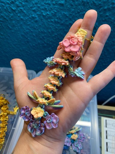 Hand hält kunstvoll gestalteten Haarreifen mit bunten Blüten und Blättern.