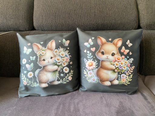 Zwei Kissen mit niedlichen, blumenschmückenden Hasenillustrationen.